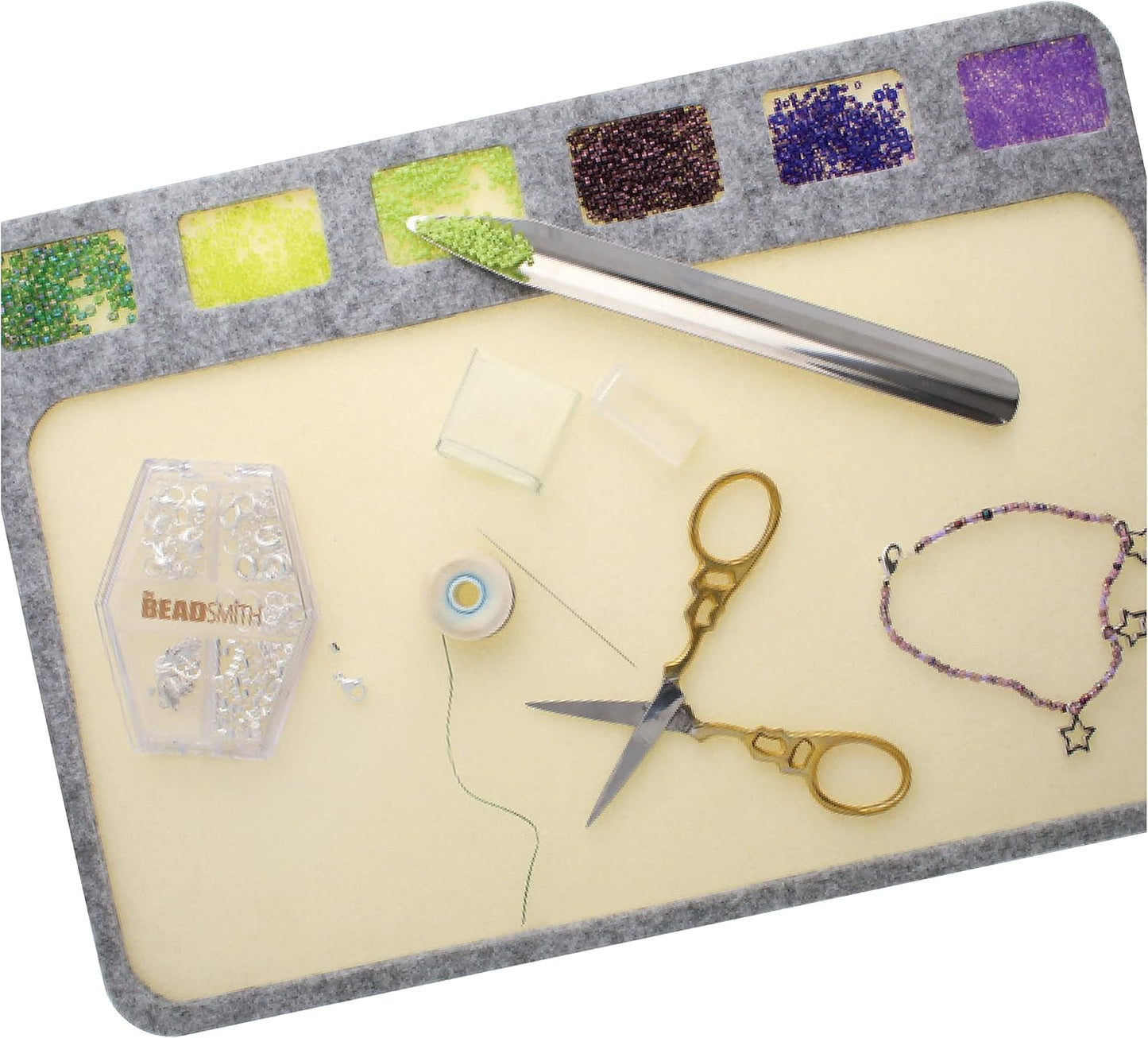 BeadSmith bead board with beads, scissors, tool, thread, and clasps for jewelry making.