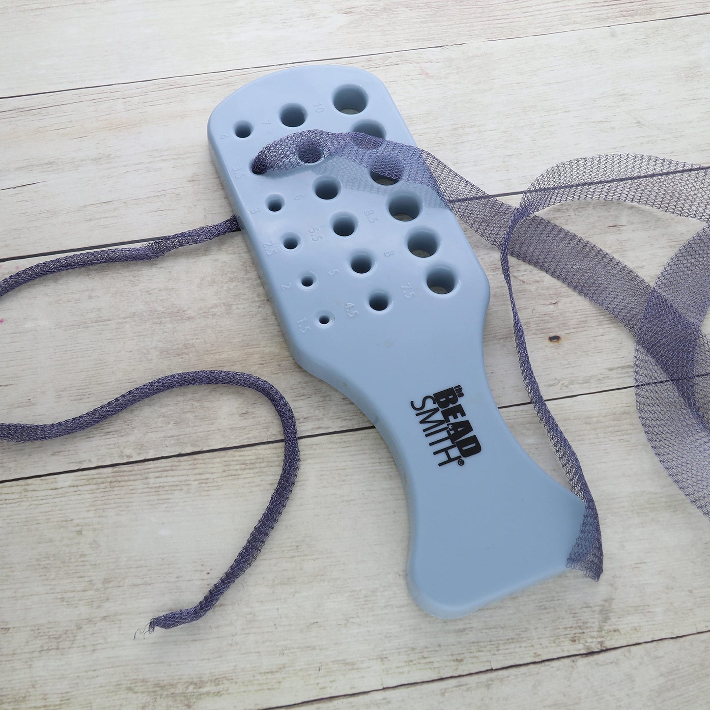 Beadsmith wire rounder plate with sizing holes and purple wire for jewelry making.