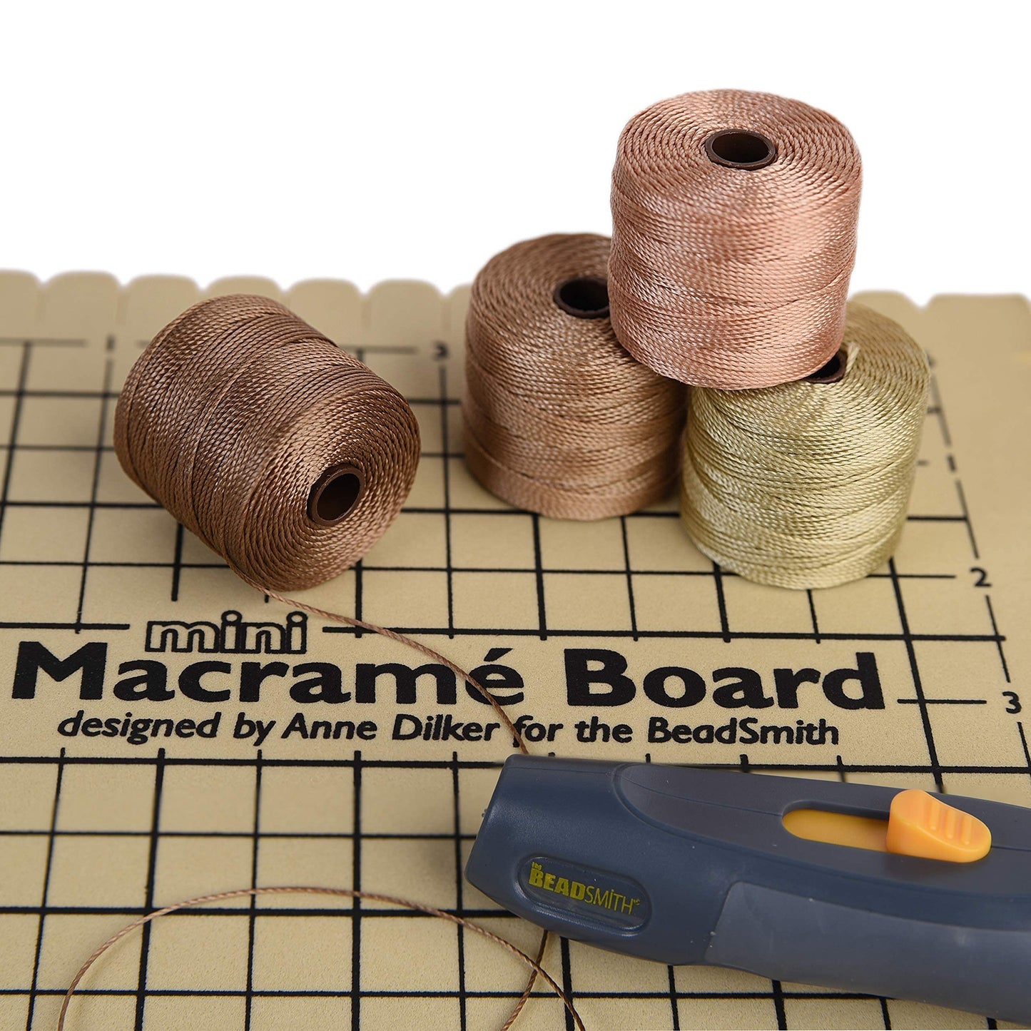 Beadsmith Mini Macrame Board with cords and thread cutter, crafting supplies.