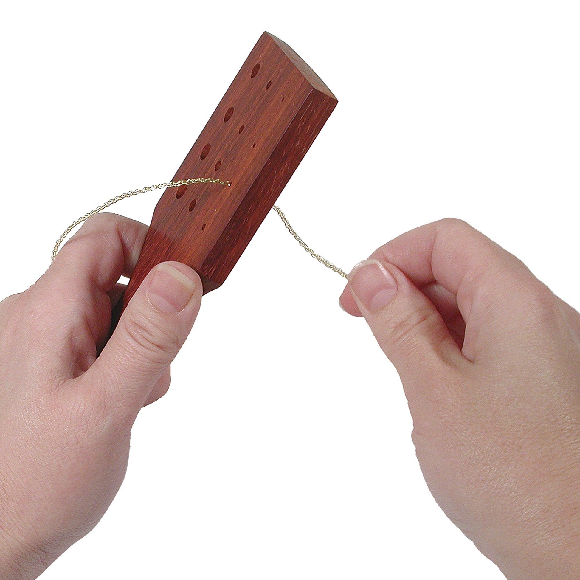 Hands threading a gold string through a wooden cribbage board with multiple holes.