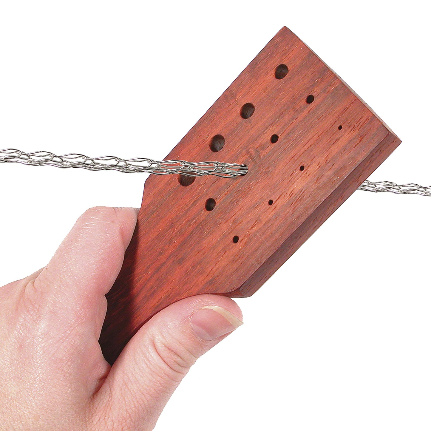 Hand holding a wooden guitar headstock with tuning machine holes and steel strings.